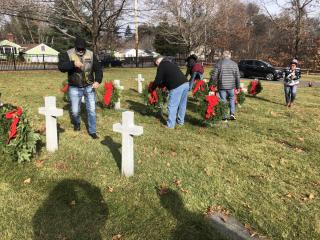 Picture of people putting Wreaths on crosses in cemetery